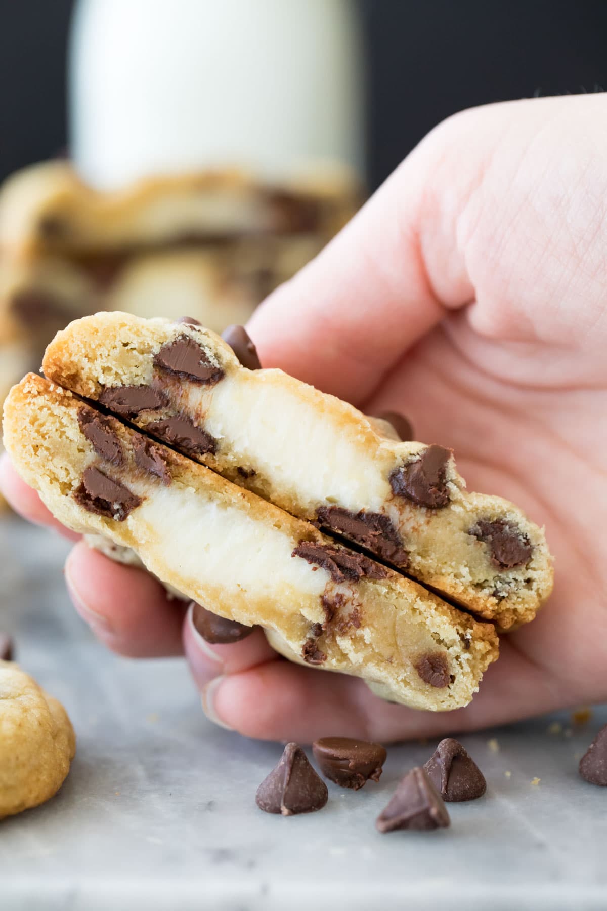 hand holding a cheesecake stuffed cookie that's been sliced in half, showing its creamy interior