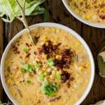 Overhead of corn chowder in bowl with toppings