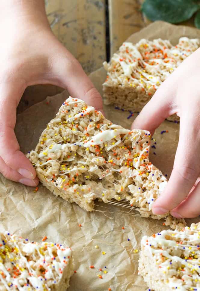 Hand pulling apart pumpkin spice rice krispie treats