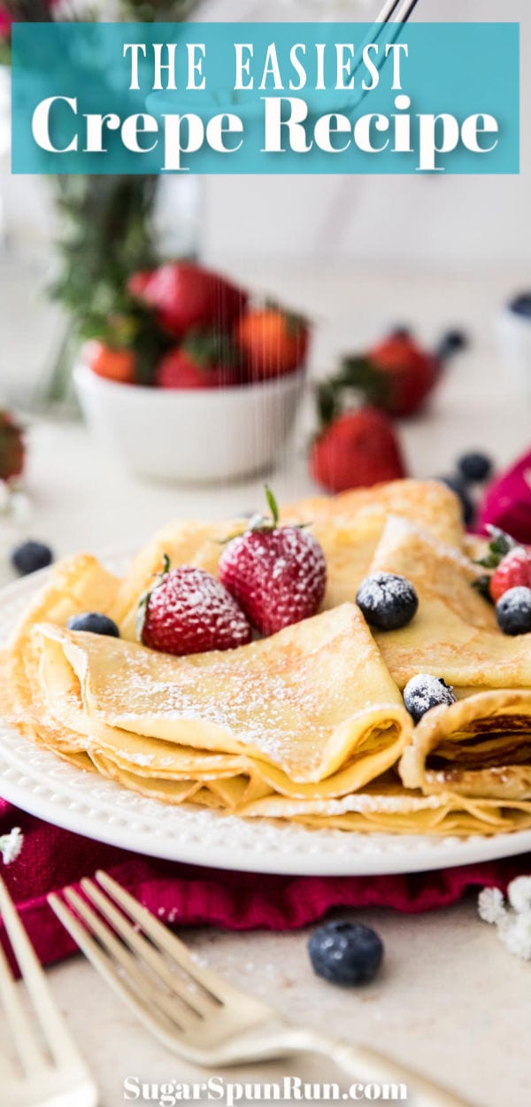 folded crepes with powdered sugar and strawberries on a white plate
