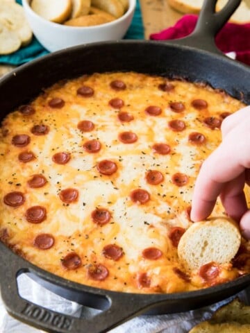 Slice of bread dipped in skillet of pizza dip