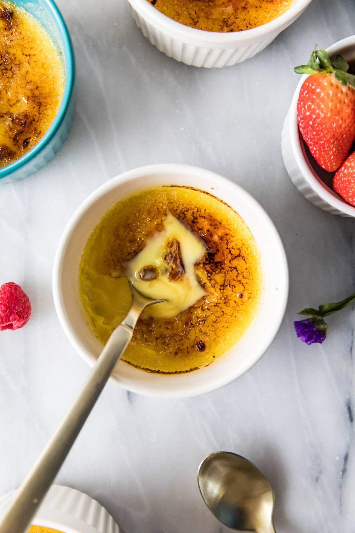 Overhead of creme brulee in a ramekin - golden spoon broke through surface to show custard beneath
