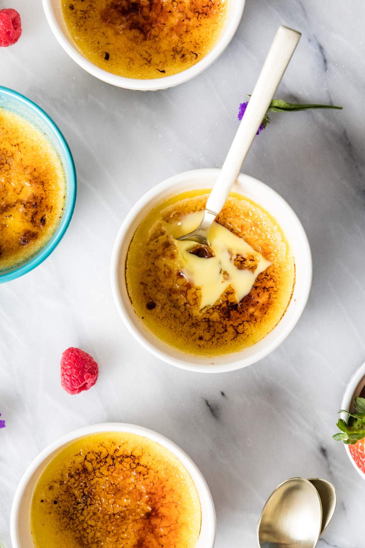 Overhead of creme brulee in a ramekin - golden spoon broke through surface to show custard beneath