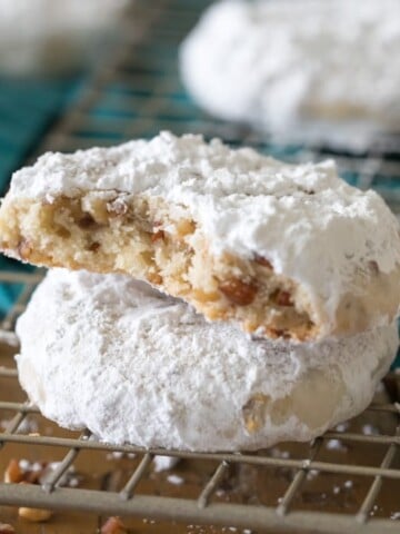 Pecan sandies stacked on top of each other on wire cooling rack with bite taken out.