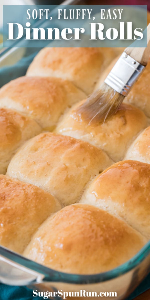Dinner rolls being brushed with butter in glass dish