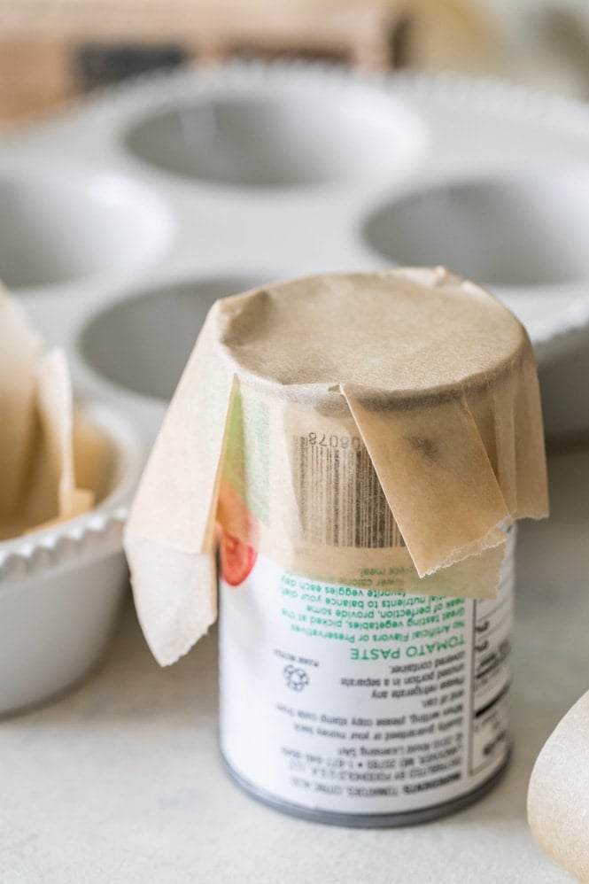 Creasing a square of parchment paper against a can of tomato paste