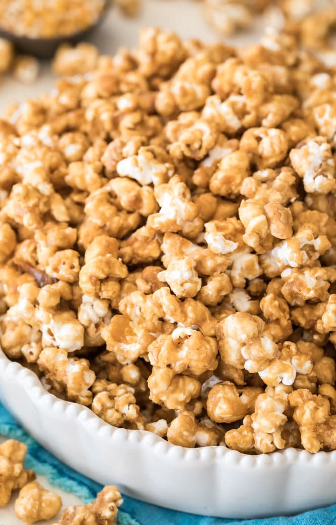 Caramel popcorn piled high in a white dish, showcasing the shiny coating.