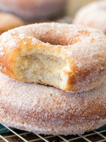 Sugared donuts stacked on top of each other. Top one has bite taken out
