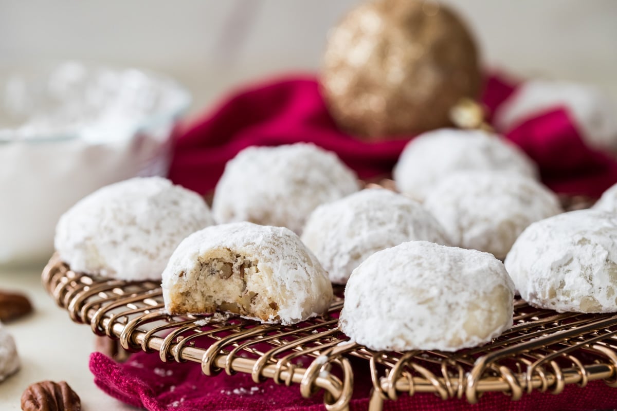 russian tea cakes on cooling rack with one cookie cut in half