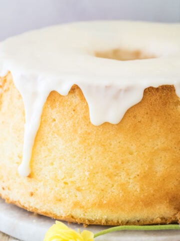 Golden chiffon cake with white glaze surrounded by a pink and yellow flower