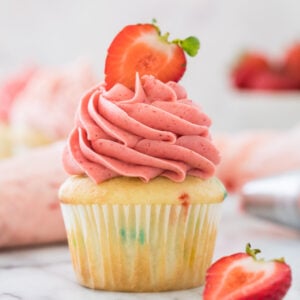 yellow cupcake with pink strawberry frosting swirled on top