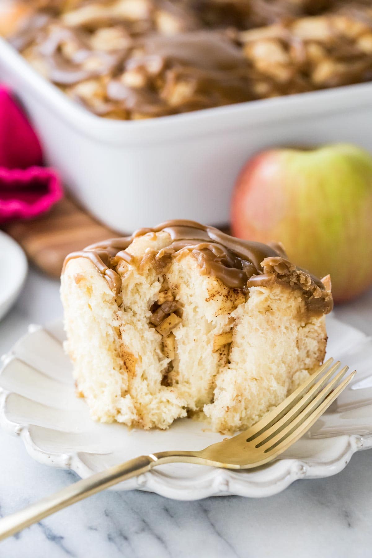 apple cinnamon roll with one bite missing on white plate