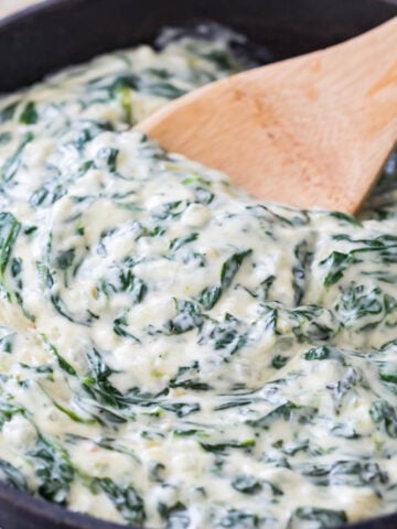 wooden spoon stirring thick and creamy creamed spinach