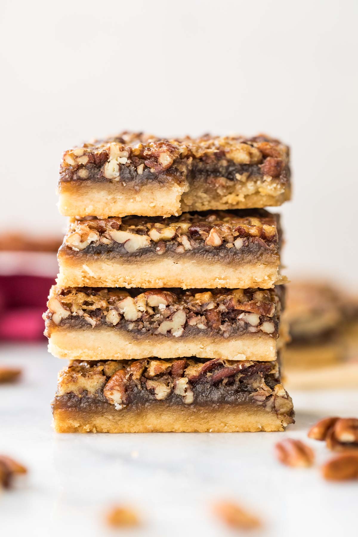 four pecan pies stacked on top of each other, with the top bar missing one bite