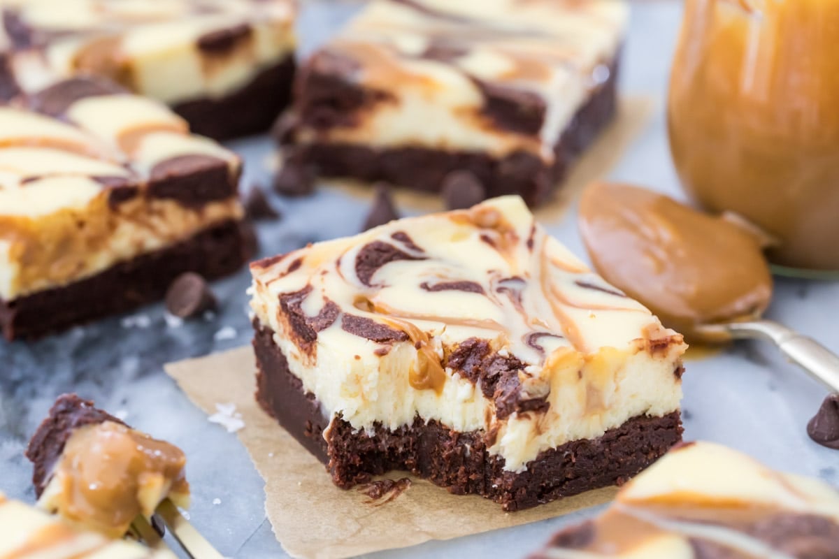 dulce de leche cream cheese brownie with one bite missing on parchment square