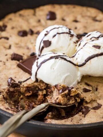 pizookie topped with vanilla ice cream being scooped into with a spoon