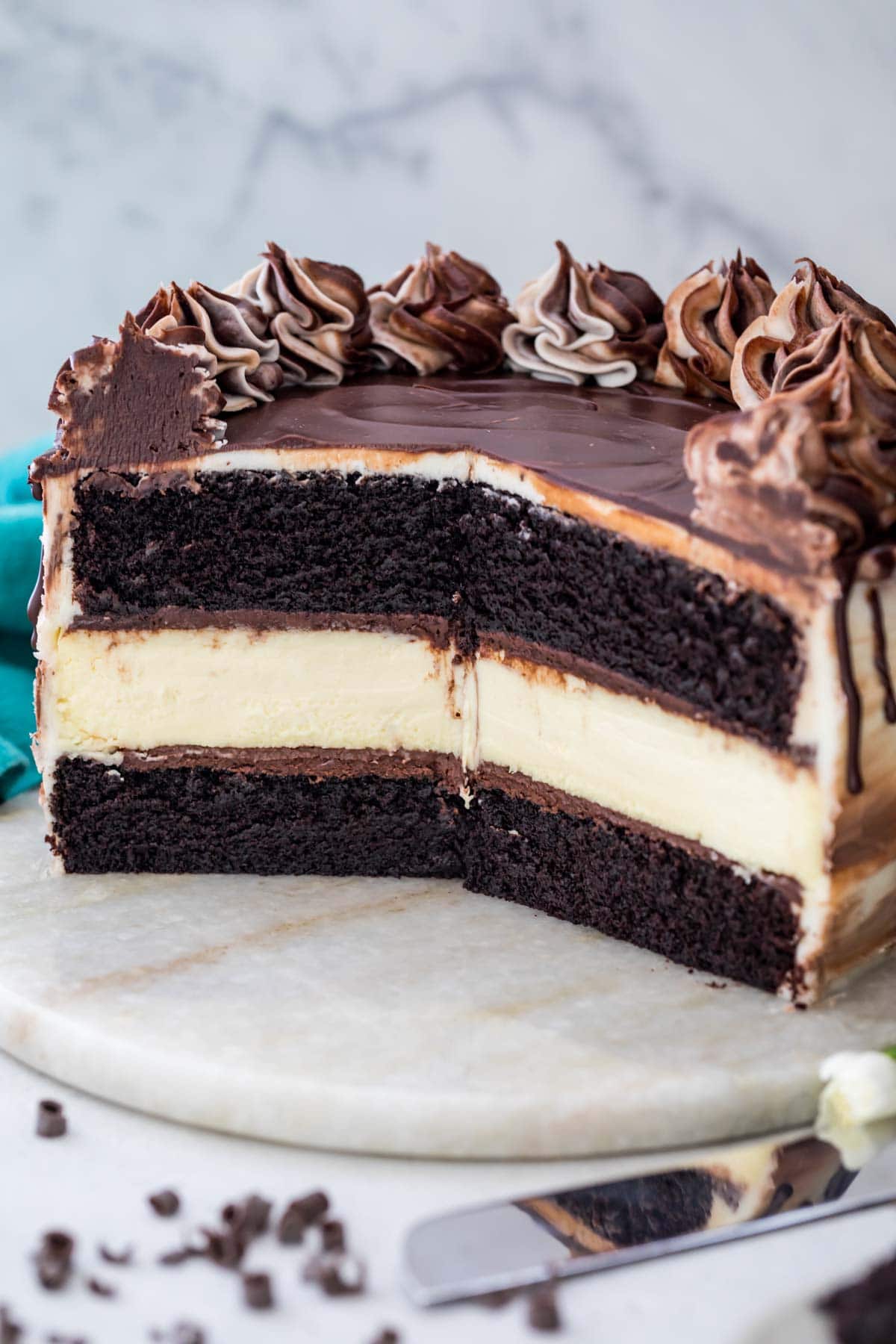 cross-section of a cheesecake stuffed cake consisting of dark chocolate cake layers sandwiching a classic cheesecake layer