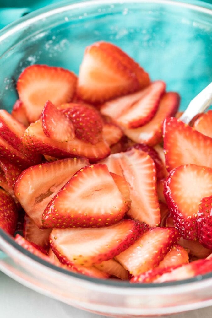 close-up shot of juicy sliced strawberries in a clear bowl