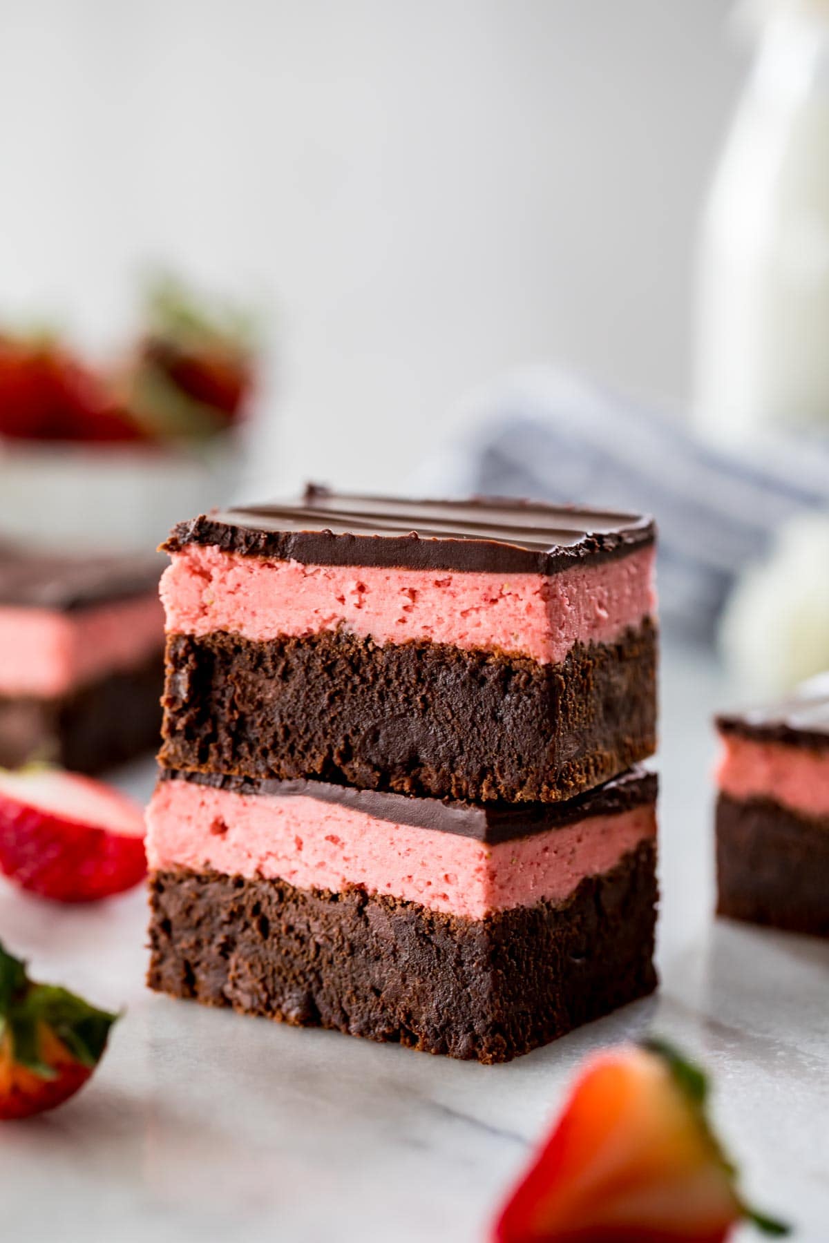 two brownie squares layered with strawberry icing and chocolate ganache stacked on top of each other