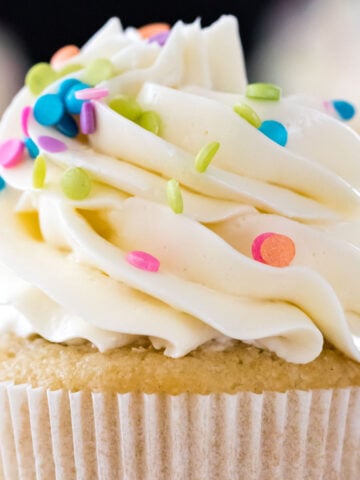 vanilla cupcake topped with piped swiss meringue buttercream and rainbow sprinkles