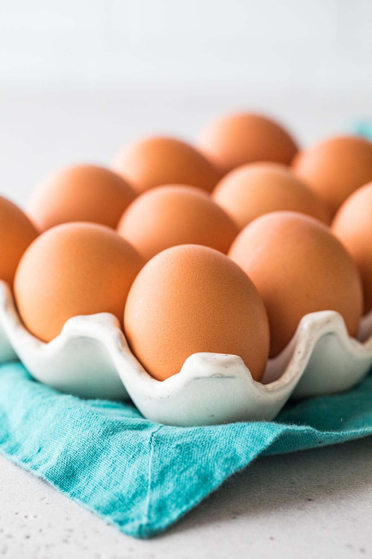 close-up view of brown eggs in an egg carton on a teal towel