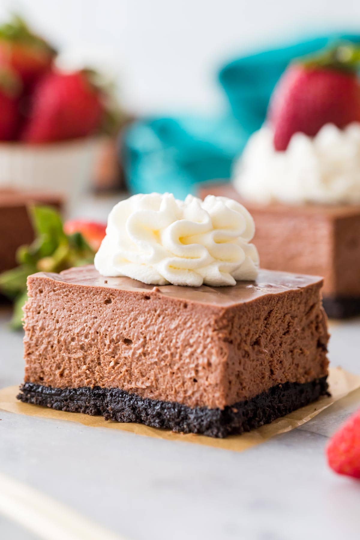 chocolate cheesecake square topped with whipped cream