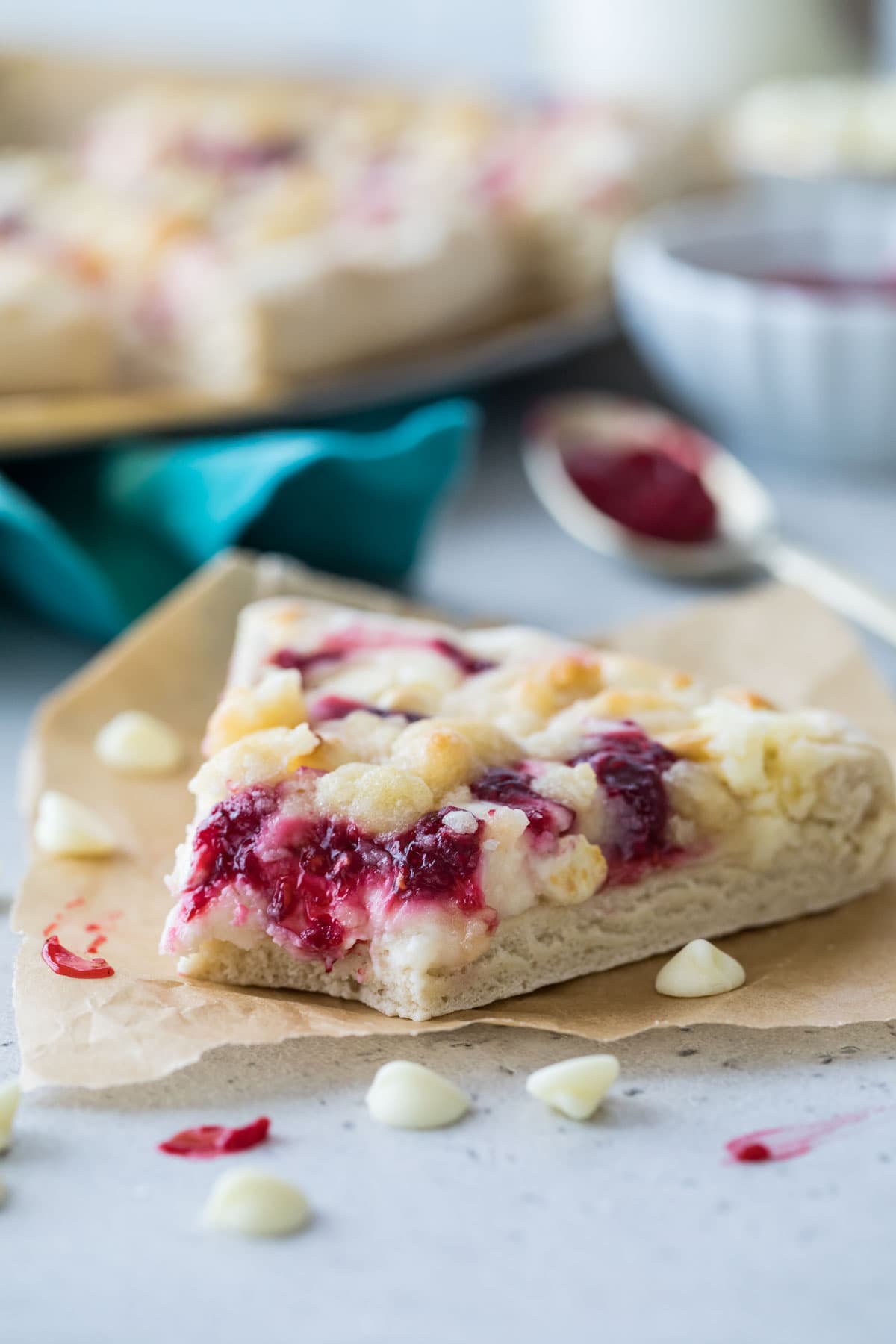 Bitten slice of raspberry pizza topped with white chocolate chips and streusel.