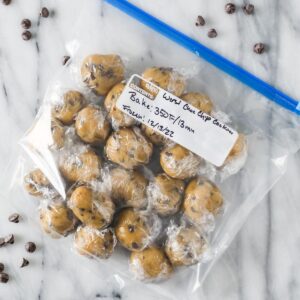 Ziploc bag of cookie dough balls that have been wrapped in plastic in preparation for freezing.