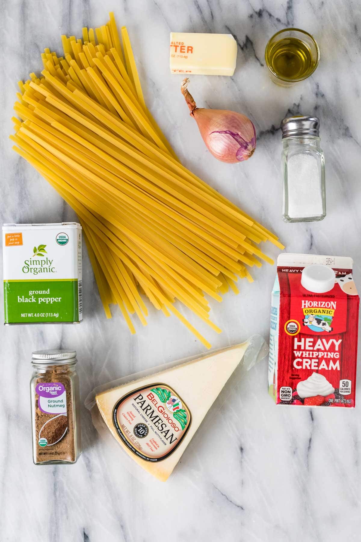 Overhead view of ingredients including fettuccine, parmesan, heavy cream, and more.