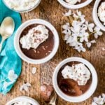 Overhead view of chocolate pot de creme topped with whipped cream and chocolate shavings in small white ramekins.