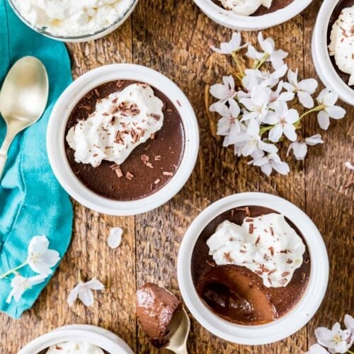 Overhead view of chocolate pot de creme topped with whipped cream and chocolate shavings in small white ramekins.