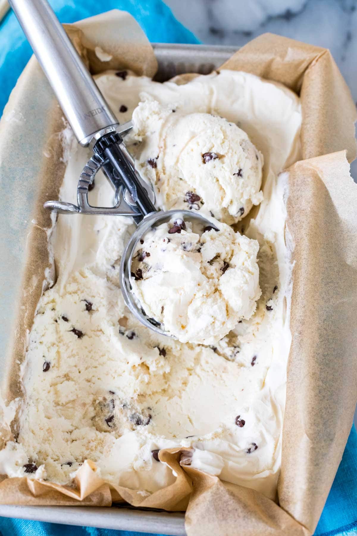 Ice cream scoop resting in a container of homemade cookie dough ice cream.
