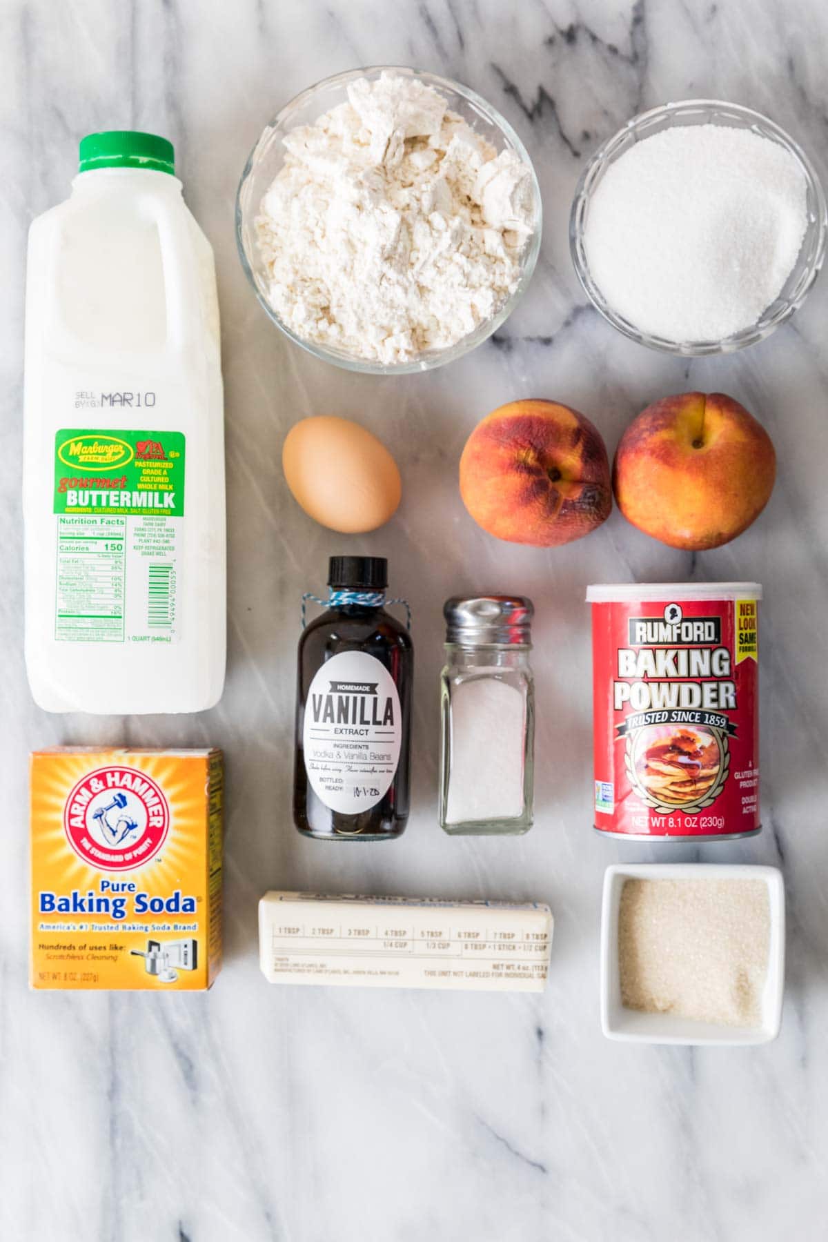 Overhead view of ingredients including buttermilk, fresh peaches, vanilla, and more.