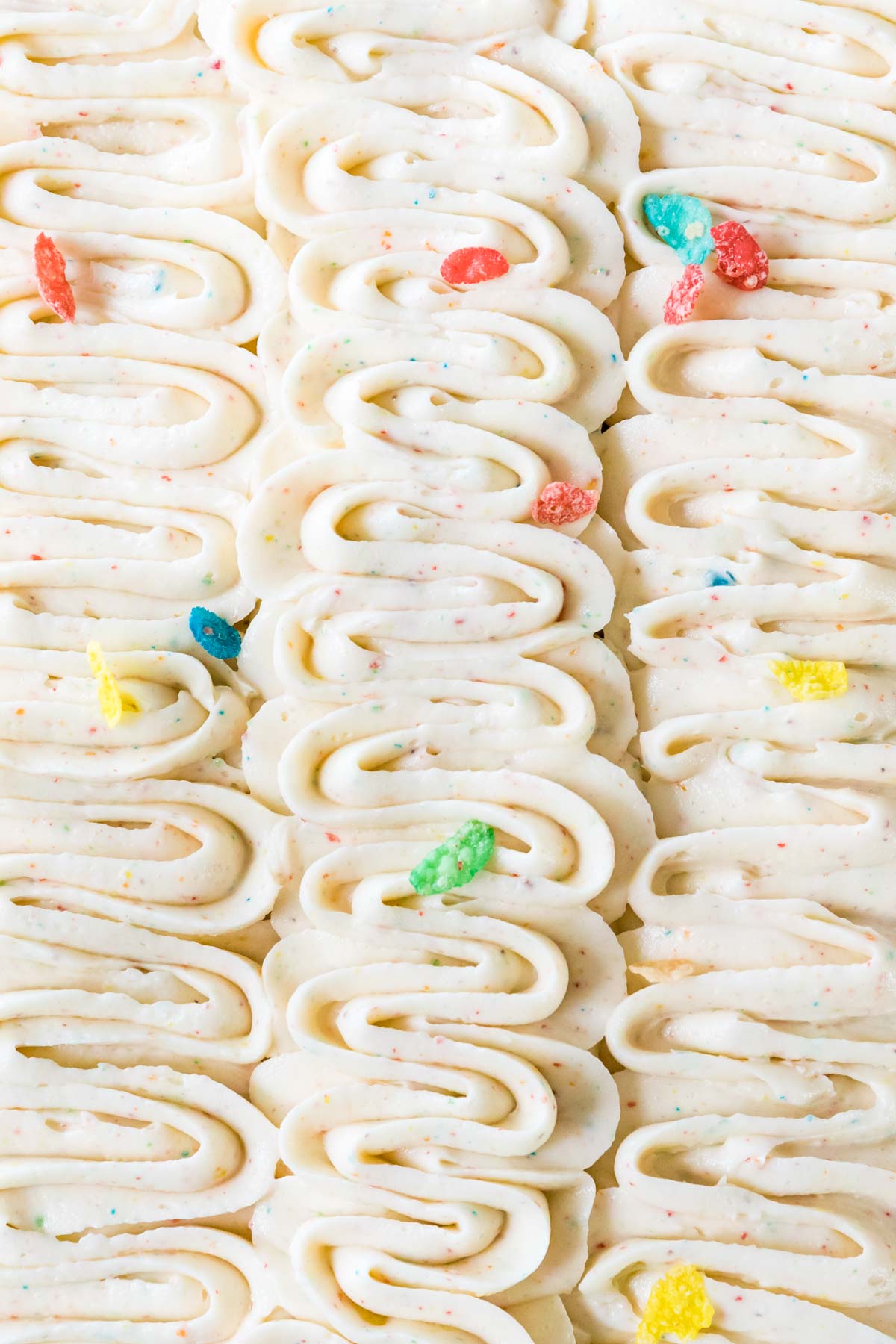 Piped ribbons of fruity pebbles frosting with fruity pebbles scattered on top.