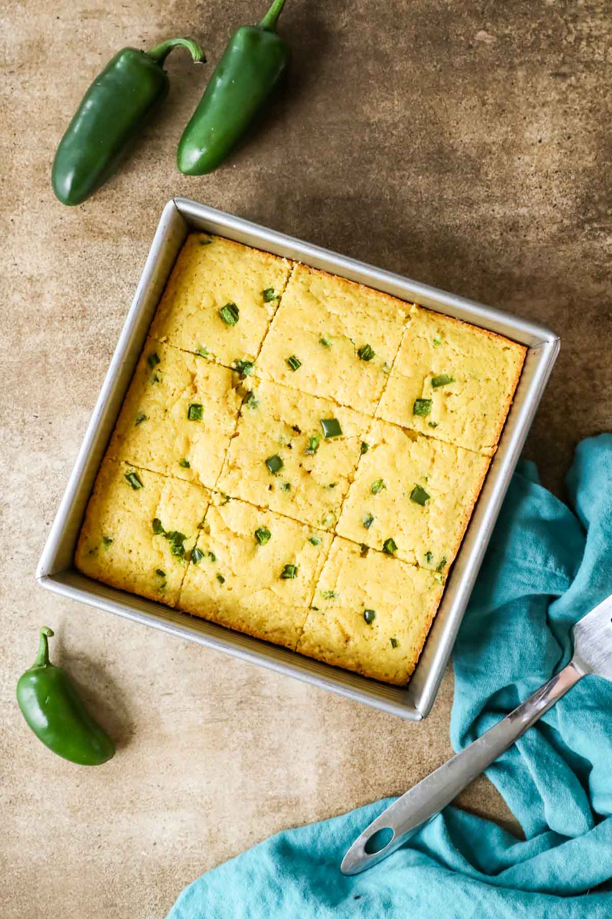 Overhead view of a square metal pan of cornbread made with jalapeno.