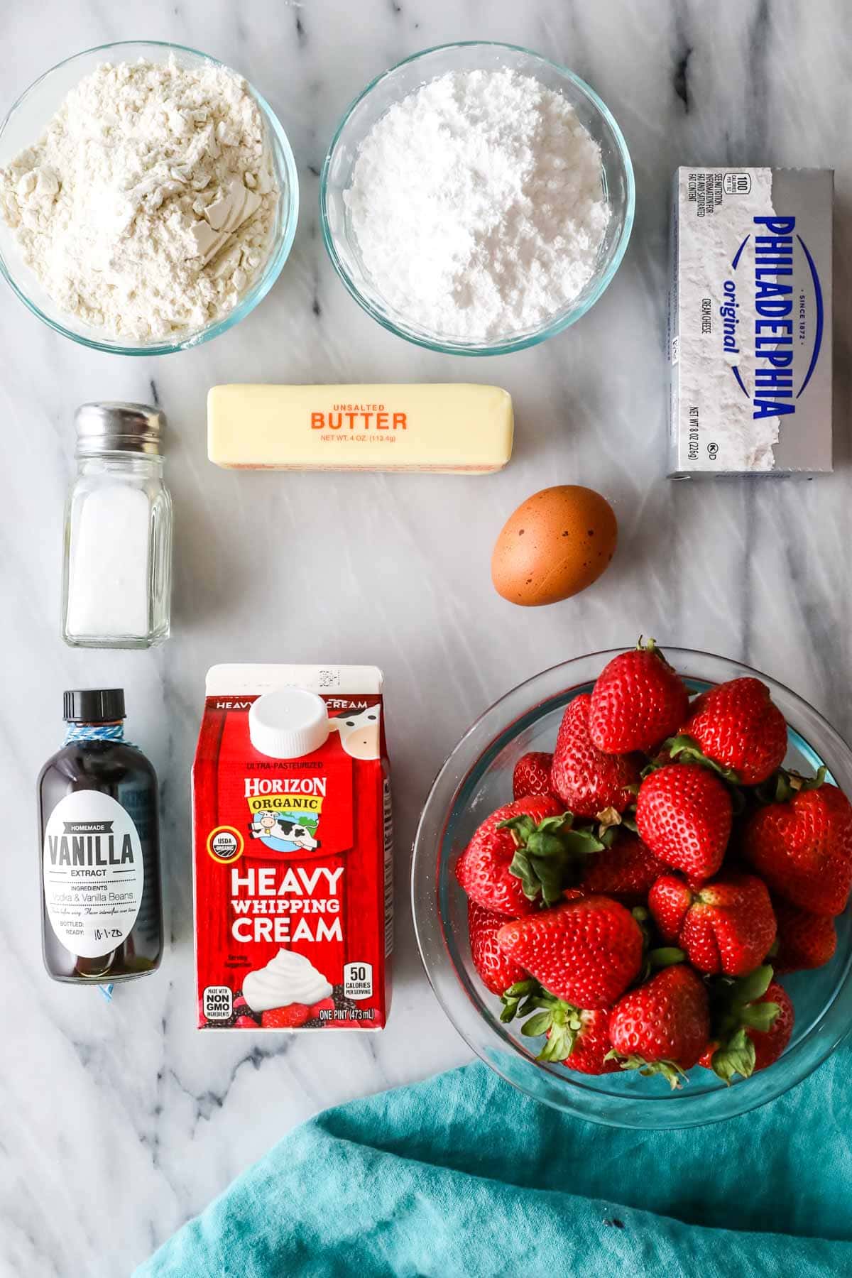 Overhead view of ingredients including strawberries, heavy cream, cream cheese, and more.