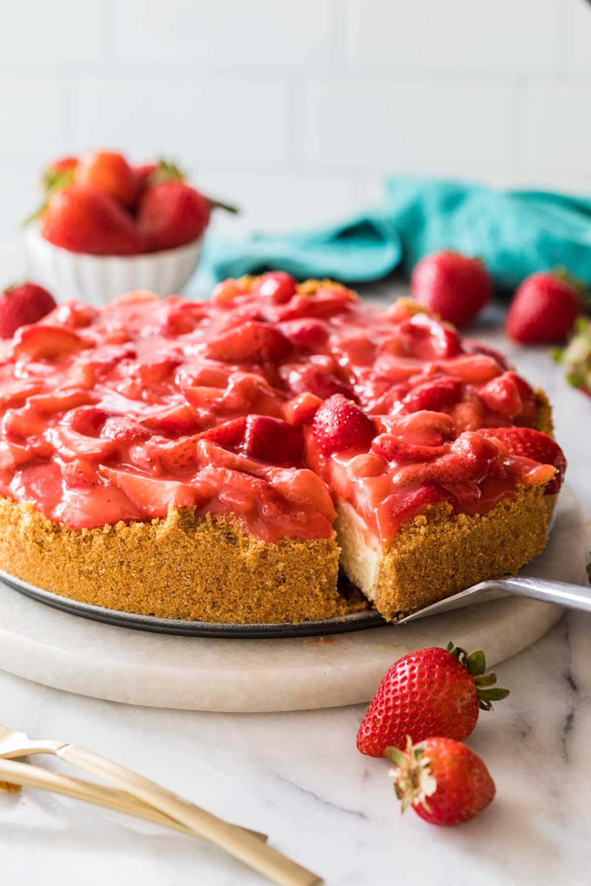 Slice of strawberry cheesecake being served from a serving platter.