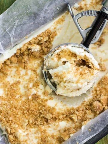 Overhead view of an ice cream scoop resting in a container of homemade key lime pie ice cream.