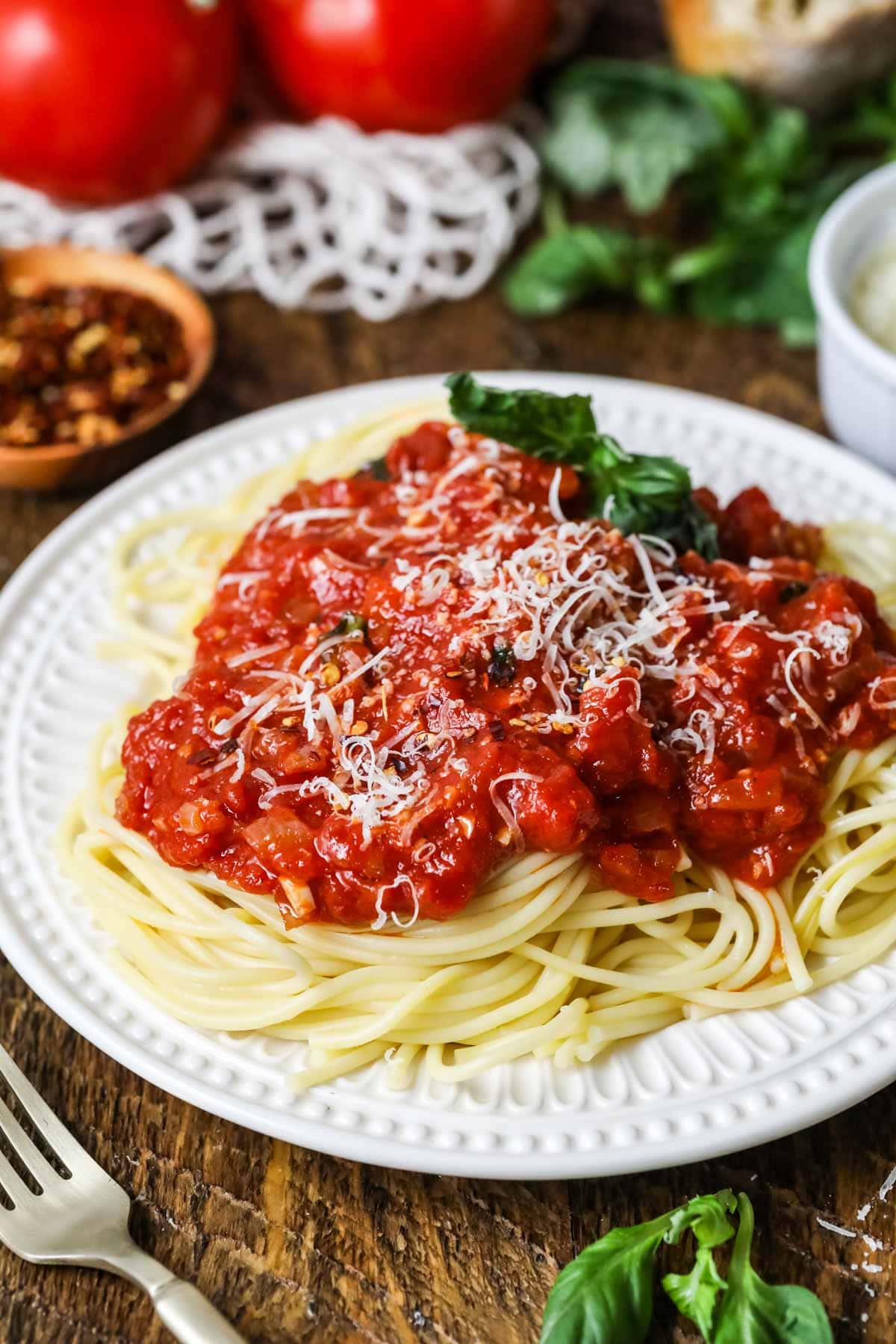 Plate of pasta topped with a spicy tomato sauce garnished with fresh basil and parmesan cheese.