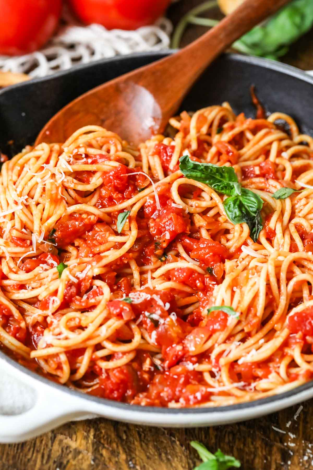 Pasta with arrabiata sauce being stirred by a wood spoon.