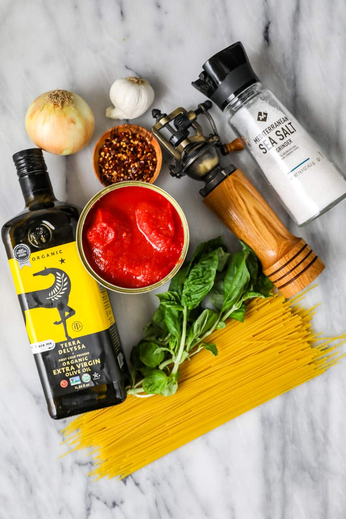 Overhead view of ingredients including olive oil, tomatoes, fresh basil, red pepper flakes and more.