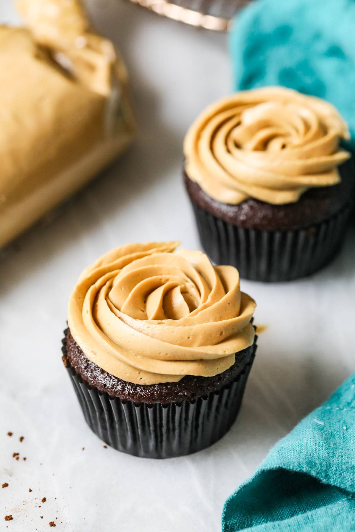 Two cupcakes piped with frosting rosettes made from coffee flavored frosting.