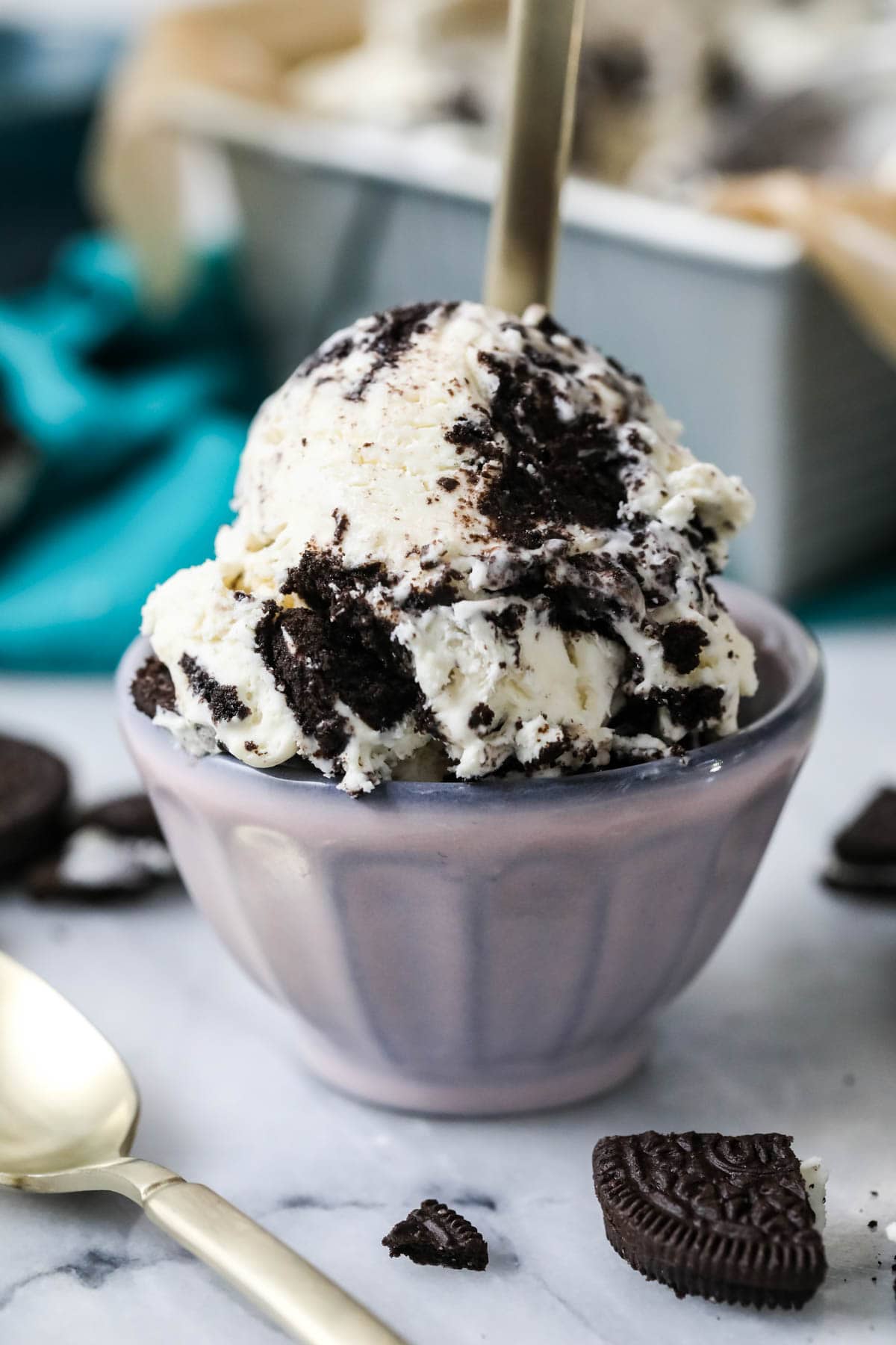 Scoop of ice cream punctuated with Oreo cookies in a small purple bowl.