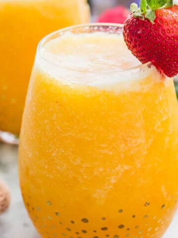 Frozen peach bellini in a glass with a strawberry garnish.
