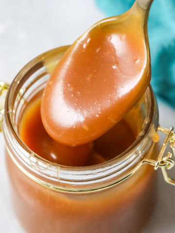 Caramel sauce being spooned out of a jar.