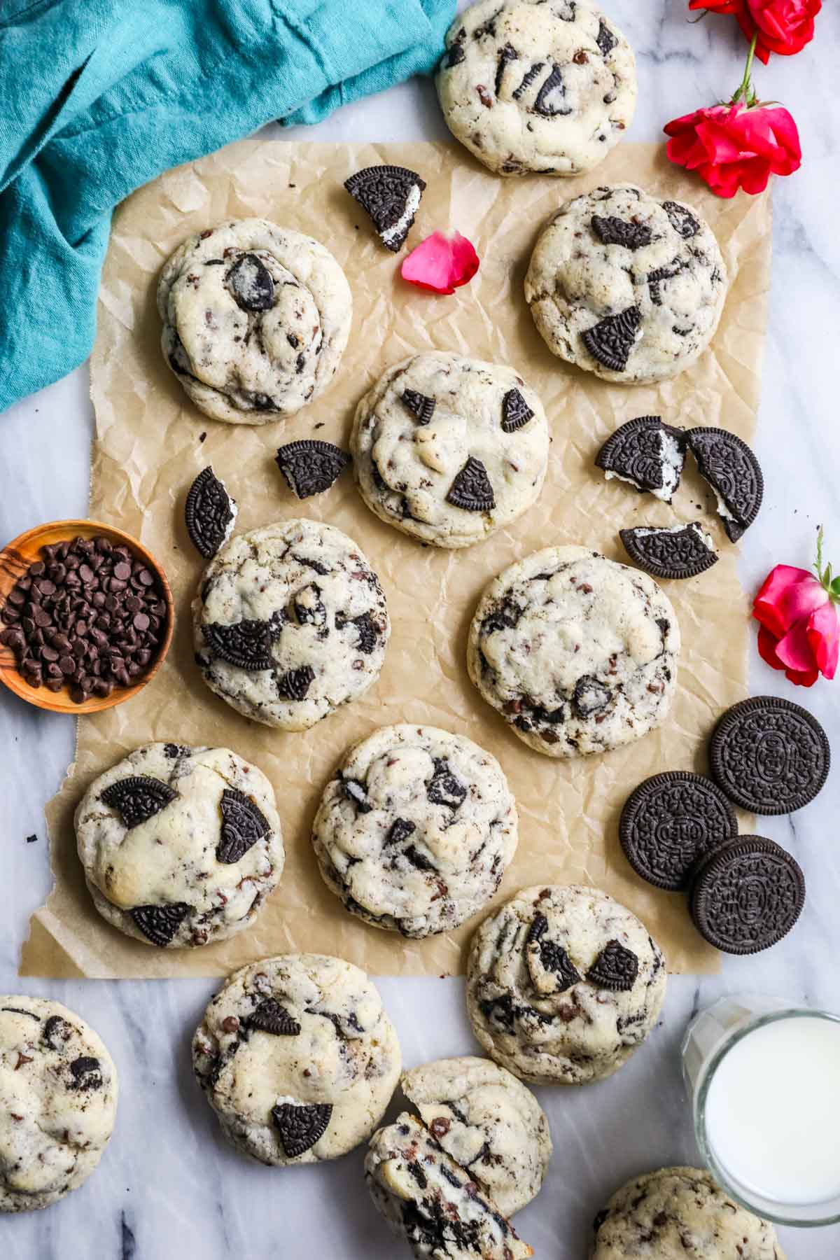 Overhead view of cheesecake stuffed Oreo cookies on a countertop with Oreo cookies and rose petals scattered throughout.