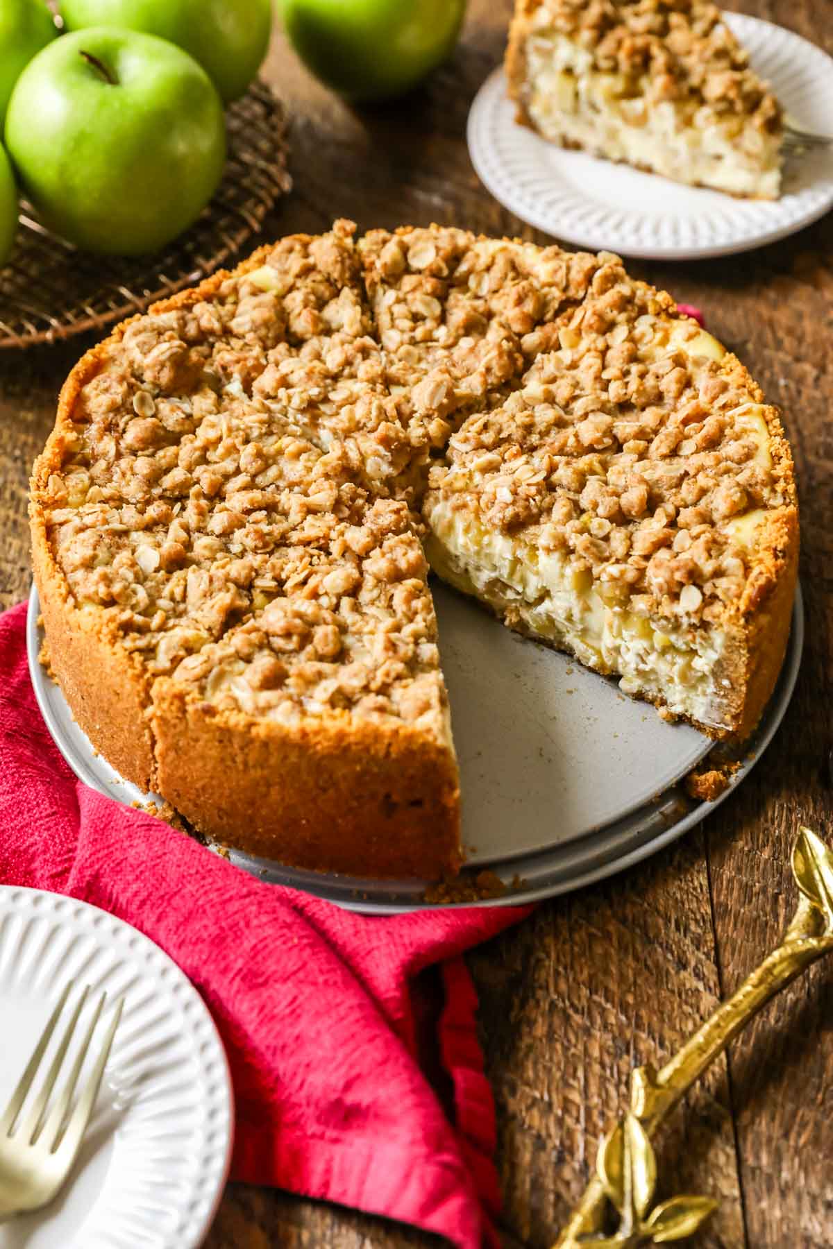 Whole apple pie cheesecake that's been cut into slices with one slice missing.