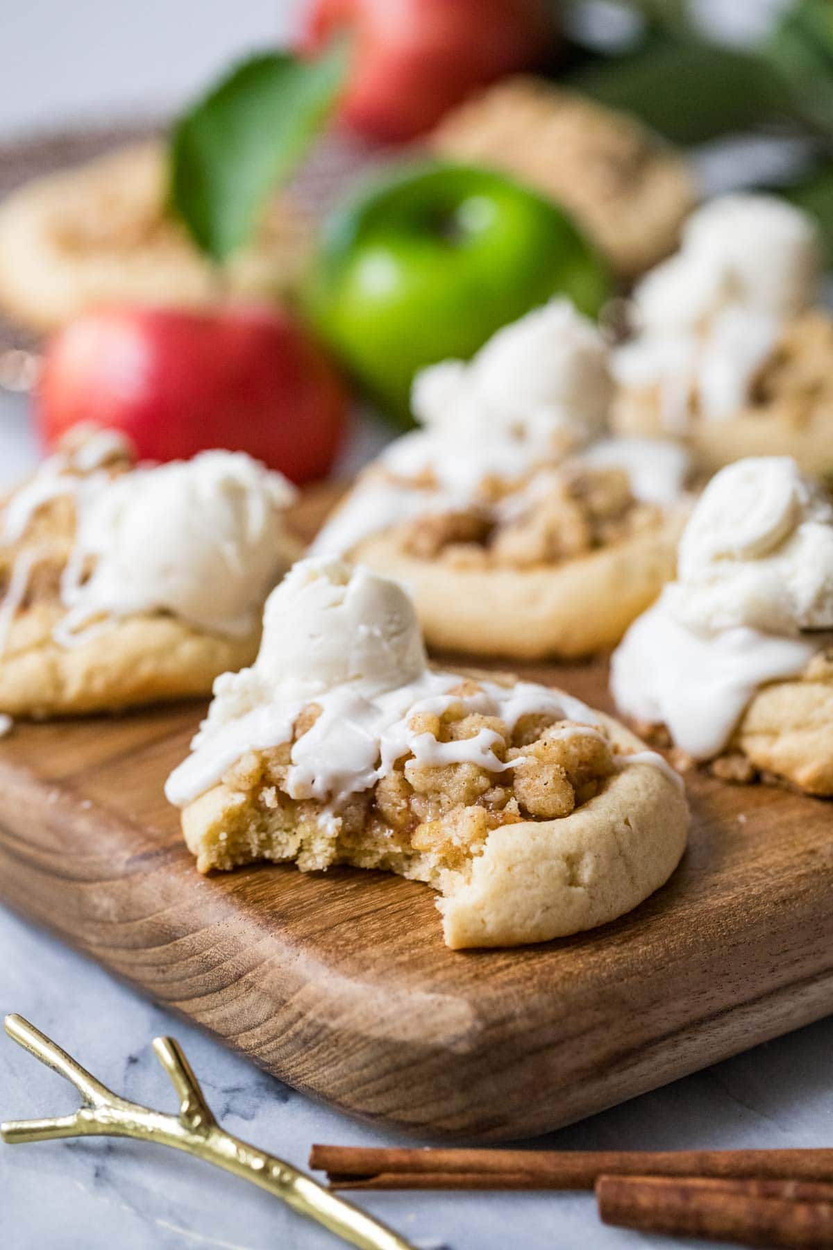 One bite missing from a cookie made with an apple pie filling, streusel, glaze, and a scoop of buttercream "ice cream".