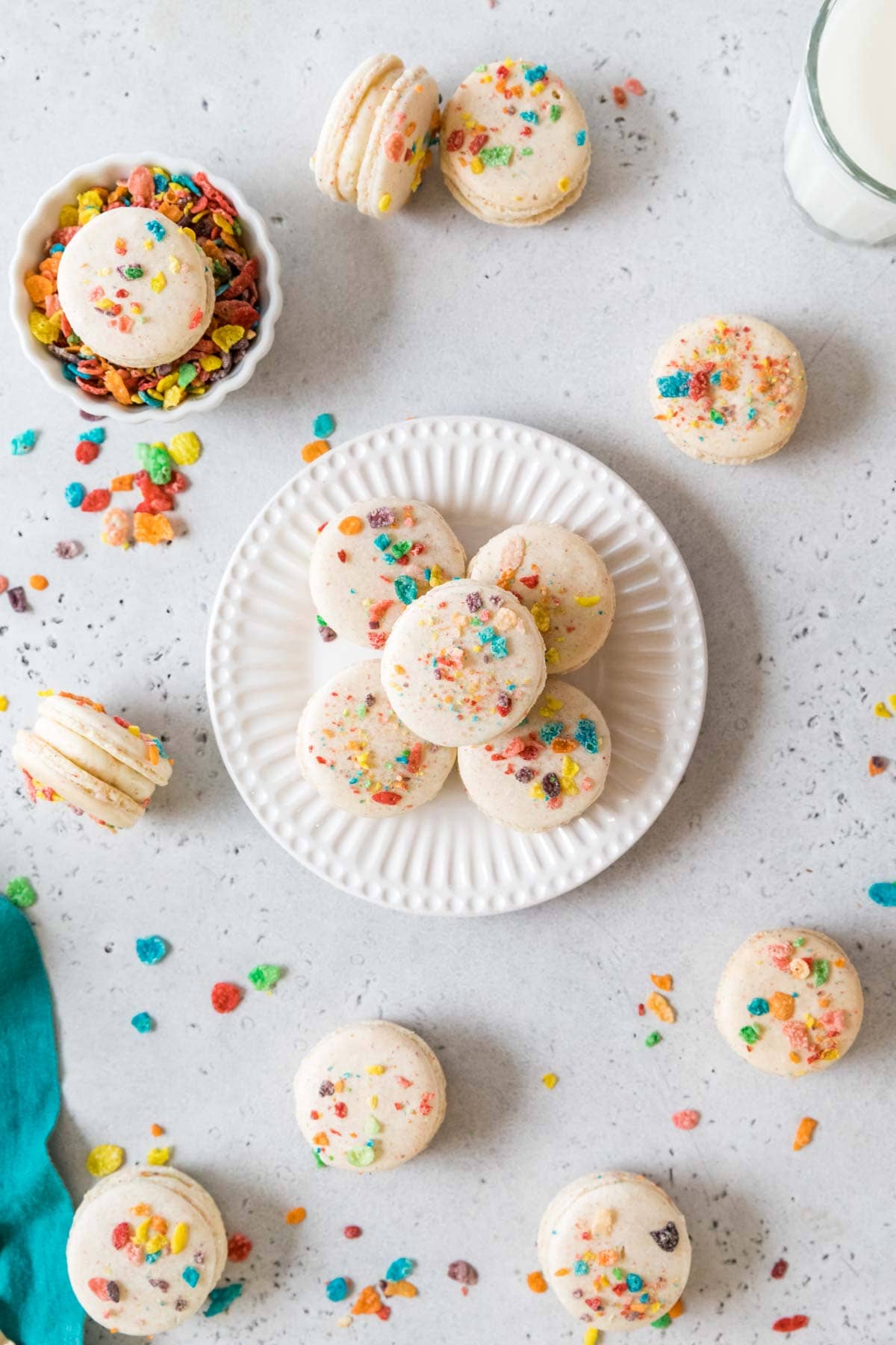 Overhead view of a plate with three macarons made with fruity pebbles arranged on top.