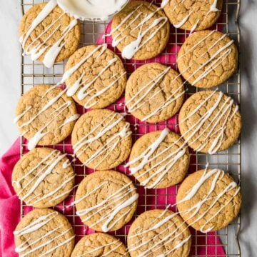Overhead view of spice cookies topped with a vanilla glaze drizzle on a cooling rack.